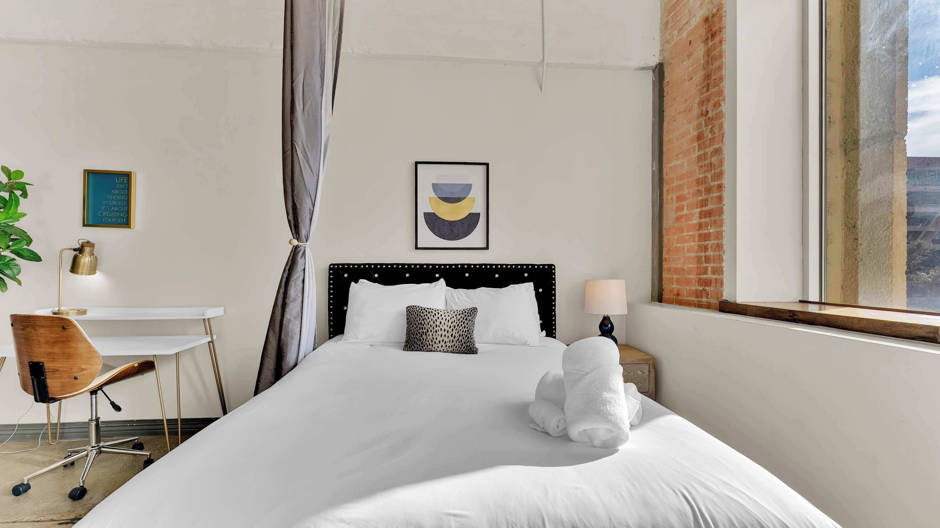 A neatly arranged hotel room with a bed, a desk, a chair, and a window with a view.