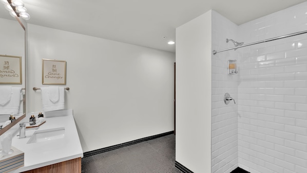 A modern bathroom with a white sink, mirror, and shower area.