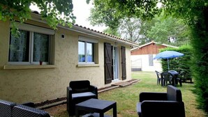 A building with a patio area featuring outdoor furniture and a blue umbrella. - Gite DE LA Grange - Vensac (VENSAC)