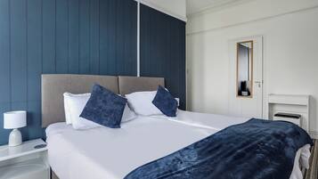 Ein Hotelzimmer mit einem Bett, einem Nachttisch, einer Lampe und einem Spiegel.