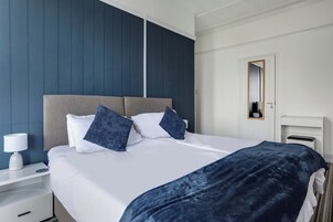 Una habitación de hotel con cama, mesita de noche, lámpara y espejo.