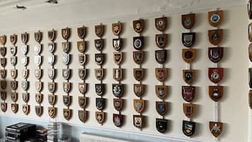 Eine Wand mit zahlreichen Holzschilden, verziert mit verschiedenen Wappen.