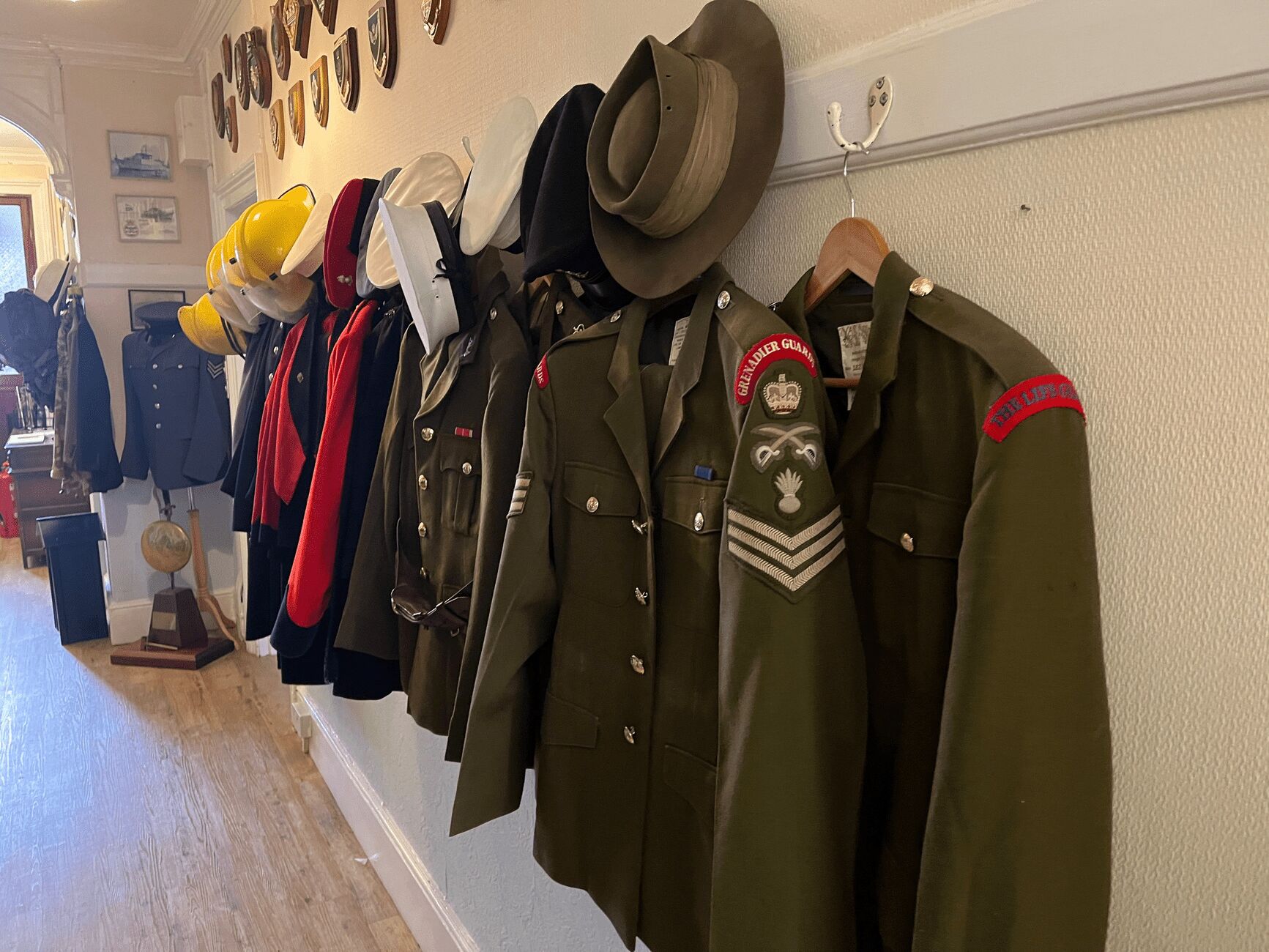 Una colección de uniformes militares y sombreros colgados en una pared.