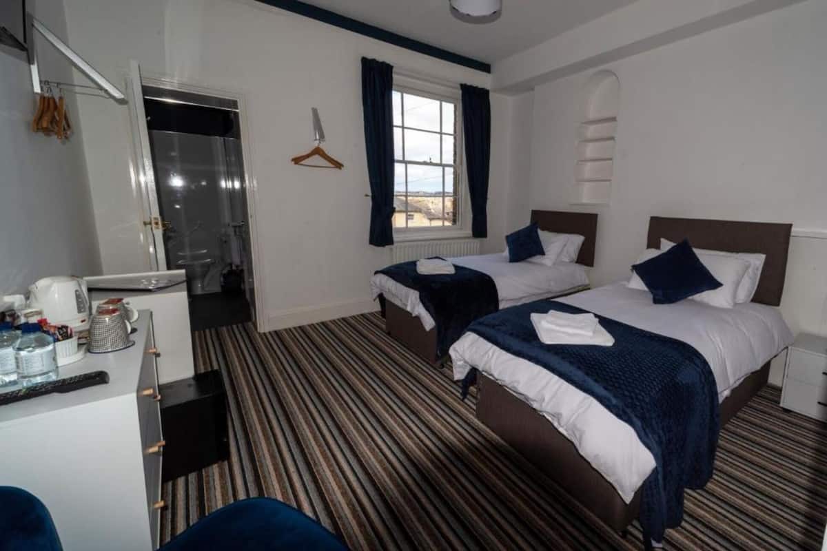 A hotel room with two beds, a bathroom, and a desk with toiletries.