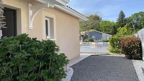 Un edificio residencial con fachada color crema, camino de entrada de grava y valla blanca.