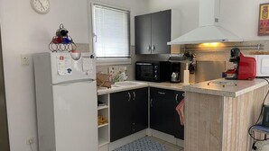 Een koelkast, een oven, een kookplaat, kookgerei, borden en bestek