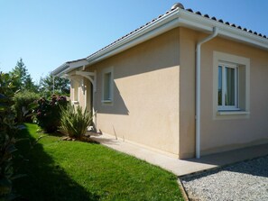 A single-story house with a beige exterior, a tiled roof, and a small front porch.