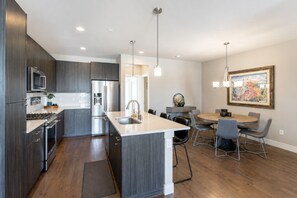 A modern kitchen with a central island, stainless steel appliances, and a dining area with a round table and chairs.