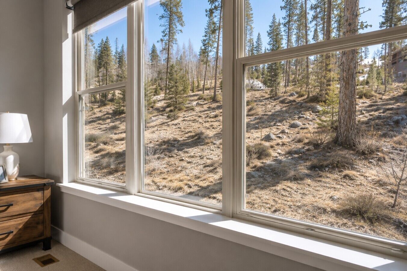 A room with a large window overlooking a forested hillside.