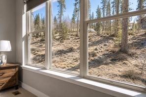 A room with a large window overlooking a forested hillside.