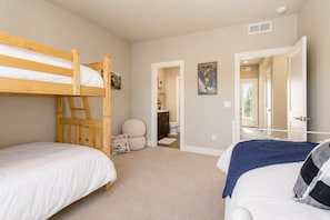 A bedroom with two bunk beds, a bathroom, and a door leading to an outdoor area.