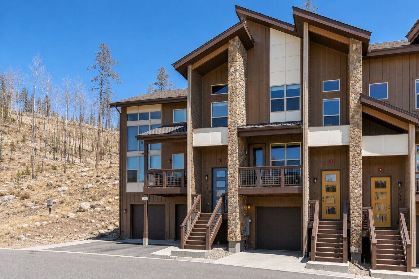 A multi-story building with a stone facade, balconies, and a parking area.