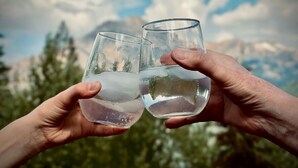 Two hands holding glasses of water against a mountainous backdrop. - Winter Park 3BR Townhouse w/ Mountain views (Fraser)