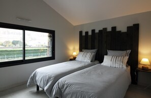 Two single beds with striped bedding, each flanked by a nightstand with a lamp, offer a restful retreat.