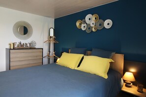A bedroom with a bed, a dresser, a mirror, and wall decorations.