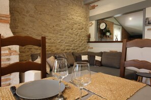 A dining area with a stone wall, a sofa, and a clock on the wall.