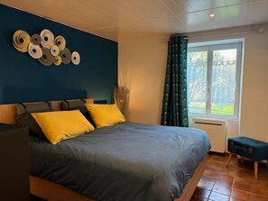 A bedroom with a bed, a nightstand, a window with curtains, and a wall decoration.