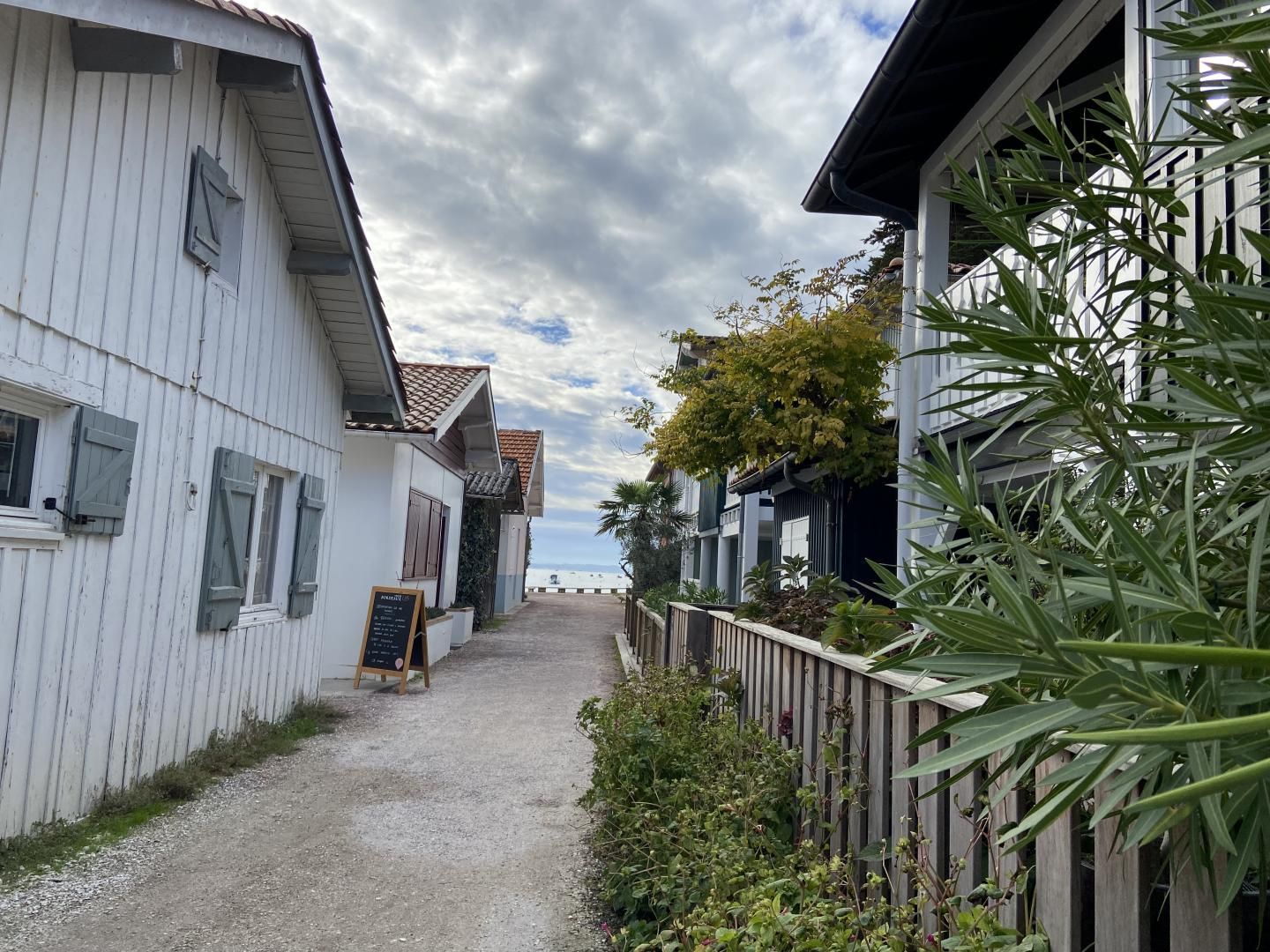 A narrow pathway leading to a building with a white facade and a tiled roof.