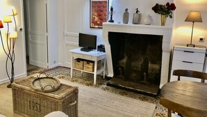 A cozy living room with a fireplace, a white desk, and a wicker basket.