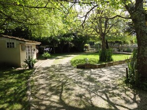Um jardim com um caminho que leva a um edifício, cercado por árvores e vegetação.