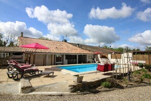 Um imóvel residencial com piscina, área de estar externa e telhado cer âmico.