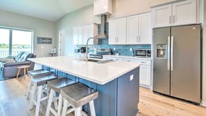 Una cocina moderna con una isla central, electrodomésticos de acero inoxidable y un ventanal grande.