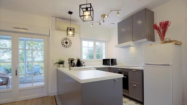 A modern kitchen with a large island, built-in appliances, and a view to the outdoors. - Le Jura - Saint Emilion (SAINT EMILION)