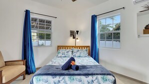 A neatly arranged bedroom with a bed, a chair, and a window with curtains.