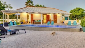 A house with a covered patio, a swimming pool, and outdoor seating.