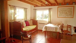 Una habitación acogedora con una cama, una mesa con sillas, un radiador y una ventana con cortinas.