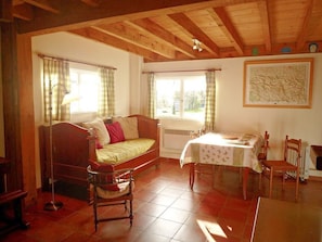 A cozy room with a bed, a table with chairs, a radiator, and a window with curtains.