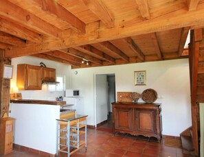 A rustic kitchen with wooden beams, a white countertop, and a small island with a sink.