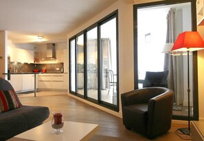 A modern living room with a sofa, a coffee table with a glass, and a floor lamp.