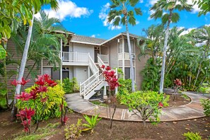 A two-story building with a white exterior and a covered outdoor area. - Grand Champions | Ocean View 2 BR | Car Incl. w/ 6+ Nights | GCH-120 by KBM (Wailea)