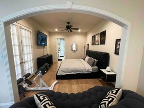 Relax in this serene bedroom with a large bed, ceiling fan, and mounted TV.