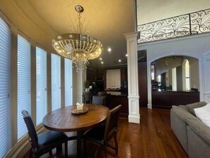 Enjoy meals in this stylish dining area with a round table, chandelier, and large window.