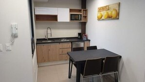 A compact kitchen with a dining area, wooden cabinets, a microwave, and a small table with chairs. - Study area Artz Pedregal, Hospital Ángeles, IPPC (Ciudad de México)