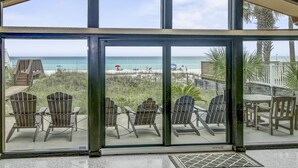 A glass-enclosed patio with Adirondack chairs and a view of the beach. - Gulf Front 3bd/2ba Home With Private Beach Access! (Panama City Beach)