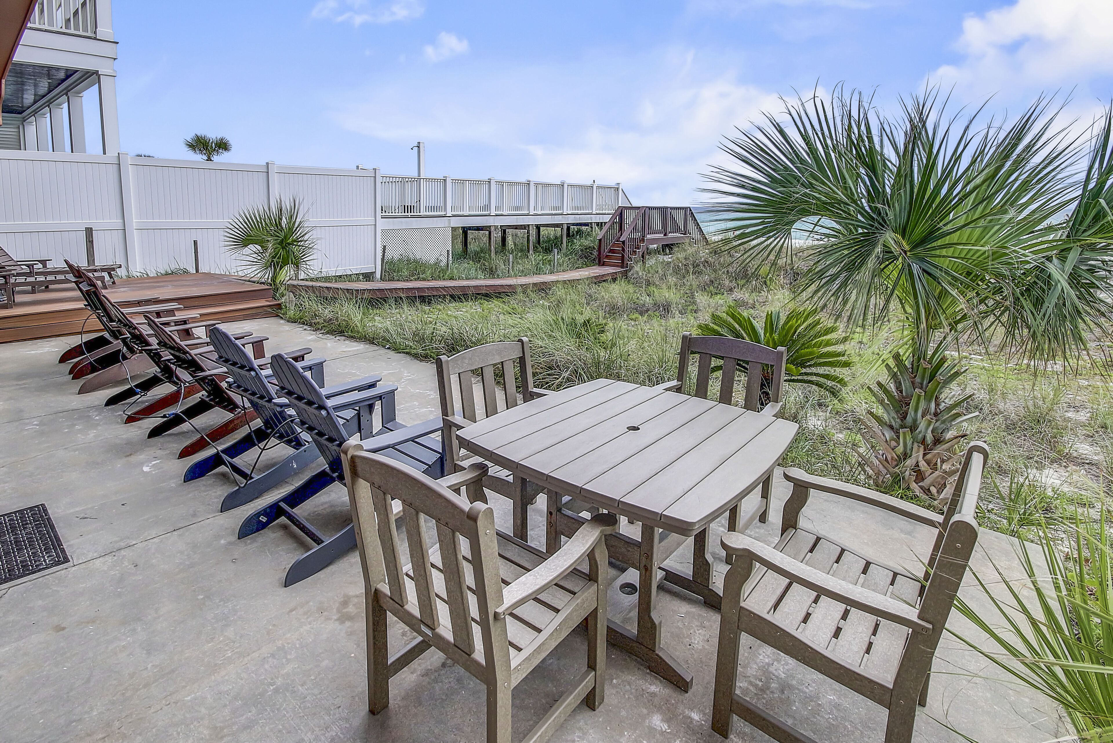 Een terras buiten met een houten tafel en stoelen, een houten terras en een palmboom.