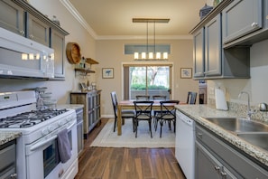 Enjoy cooking in this well-lit kitchen with a central island, oven, and stainless steel sink.