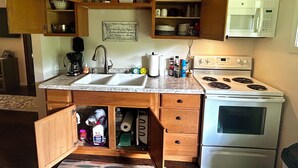 A kitchen with wooden cabinets, a double sink, a microwave, and an oven.
