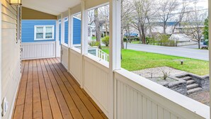 A covered porch with a wooden floor and white railings, overlooking a residential street and a grassy area. - Saratoga Springs Vacation Rental w/ Lake Views! (Saratoga Springs)