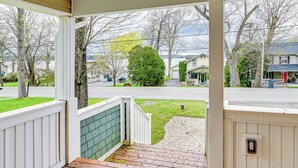 A covered porch with a view of a residential street, a green bush, and a house with a red door. - Saratoga Springs Vacation Rental w/ Lake Views! (Saratoga Springs)