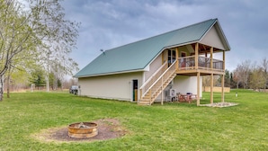 A two-story house with a balcony, a fire pit, and a covered outdoor seating area. - Cozy Solar-Powered Loft: Walk to Lake Champlain! (St. Albans Town)