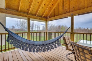 A wooden deck with a hammock, a chair, and a table. - Cozy Solar-Powered Loft: Walk to Lake Champlain! (St. Albans Town)