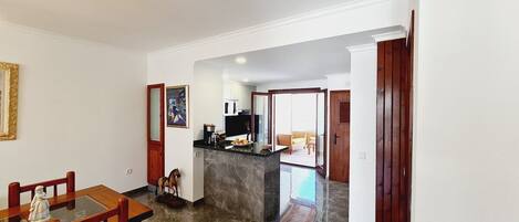 A spacious kitchen with a marble countertop and a dining area with wooden chairs.