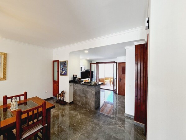A spacious kitchen with a marble countertop and a dining area with wooden chairs.