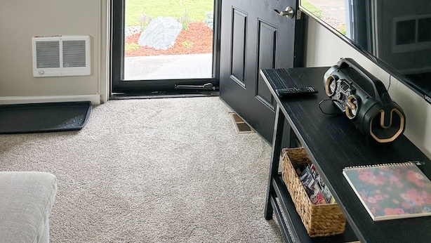 Una stanza con una porta nera, una televisione, un tavolino e un pavimento con moquette.