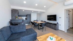 Un salon moderne avec un canapé gris, une table basse en bois et un coin repas comprenant une table et des chaises.