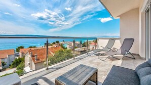 Un balcon avec vue sur la mer, deux fauteuils et une petite table.